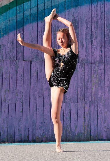 Девочка-гимнастка делает вертикальный шпагат
