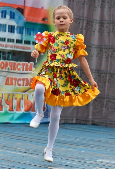 Девочка танцует народный танец на сцене.